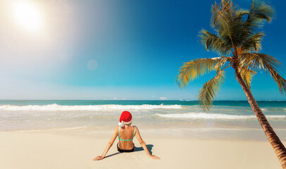 Young woman in santa hat on tropical beach Christmas vacation