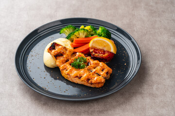 Grilled salmon fillets with mentai sauce and mash potato plating on black plate with negative space for text.