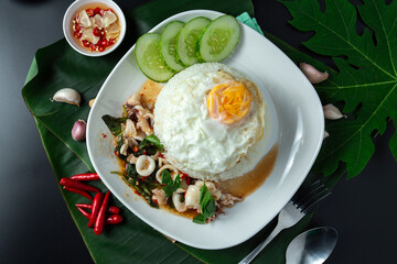 Stir Fried Basil with Squid with Rice or seafood fried rice with basil Thai food on black table, hot and spicy