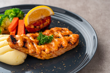 Grilled salmon fillets with mentai sauce and mash potato plating on black plate with negative space for text.