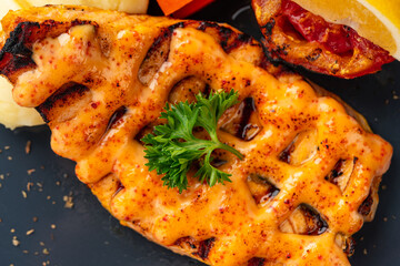 Grilled salmon fillets with mentai sauce and mash potato plating on black plate with negative space for text.