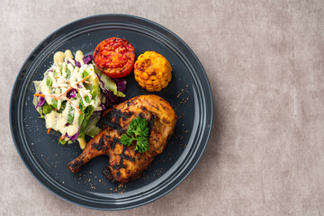 Half chicken baked in a sauce of garlic, soy, ginger, and honey.  plate with baked corn, salad and tomatoes. 