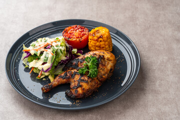 Half chicken baked in a sauce of garlic, soy, ginger, and honey.  plate with baked corn, salad and tomatoes. 