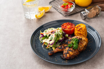 Half chicken baked in a sauce of garlic, soy, ginger, and honey.  plate with baked corn, salad and tomatoes. 