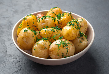 Boiled potatoes with dill and butter close-up on a dark background. Side view, horizontal