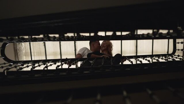 Playful interracial couple looking at the camera and having fun in apartment stairs in Madrid