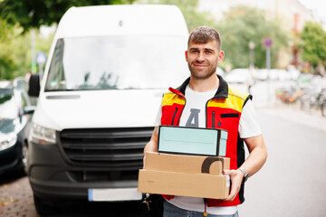 Delivery agent holding customer boxes in front of work car on city street