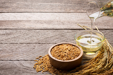 Rice bran oil with paddy rice on wooden table background. 