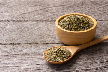 Dried Thyme leaf in wooden bowl and spoon isolated on rustic wood table background.
