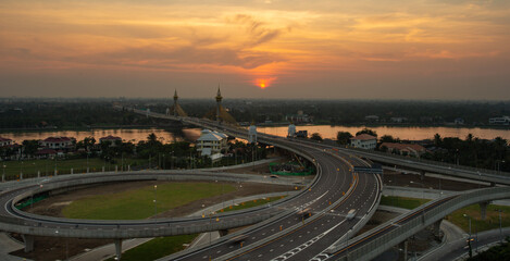 Fototapeta na wymiar Sunset over Maha Chesadabodindranusorn Bridge (Ninthaburi bridge) in the evening. The bridge over the Chao Phraya river in Nonthaburi, Thailand.