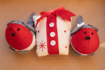 Three christmas cloth ornament composition in white, red and grey. Two birds and one present.