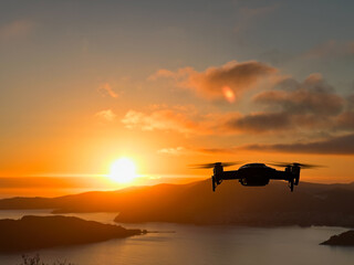 Fototapeta na wymiar Drone hovers over the sea against the backdrop of mountains at sunset