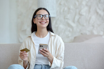 Young beautiful woman in glasses smiling and happy doing online shopping in online store sitting on...
