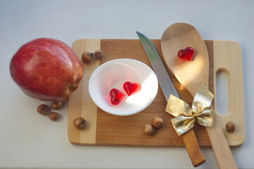 the concept of the kitchen of love is the psychology of the newlyweds' relationship. hearts, ribbons, knife, apple, spoon on a cutting board