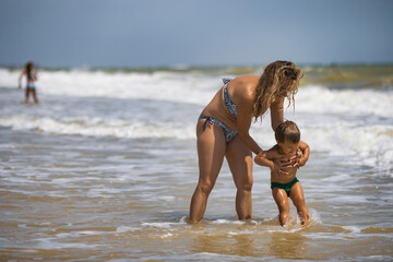 Fototapeta na wymiar Mom throws her son up over the sea on summer vacation under the warm sun