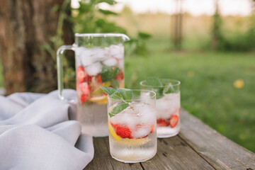 Summer drinks in stylish minimalistic glasses on wooden background in nature. Copy space.