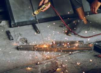 Professional worker Welding metal at workshop with electric welding rod