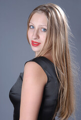 Fototapeta premium beautiful young girl with long blond hair in a black jacket on a gray background
