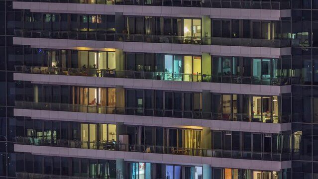 Windows lights in modern residential buildings timelapse at night. Multi-level skyscrapers with illuminated rooms inside