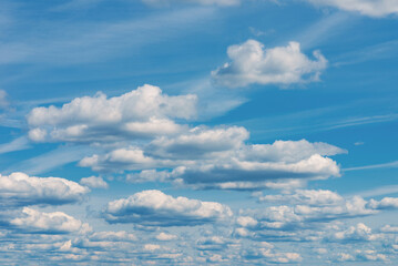 Fototapeta premium White clouds in the blue sky. White light cloudy heaven,good weather. Summer sky. Heaven and infinity. Curly clouds on a sunny day. Beautiful bright blue background.