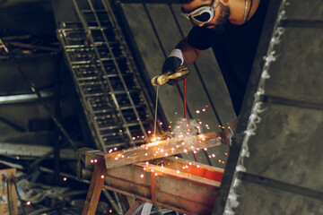 Professional worker Welding metal at workshop with electric welding rod