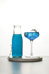 Dark blue drink in a vintage glass for sparkling wine - pea flower tea or blue curacao sirup cocktail, back lighting