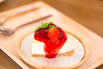 Sweet dessert and bakery concept. Strawberry cheese pie cake on a white plate on a white plate on a wooden table in the cafe.