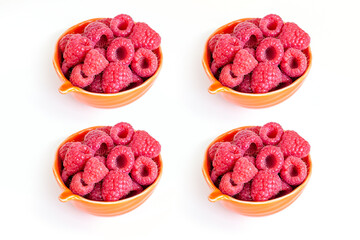 Four bowls of fresh organic raspberries isolated on white background. Healthy breakfast option.