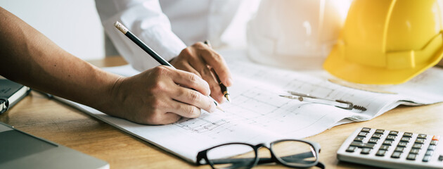 Professional home builder concept. Architects planning on the blueprint to build house.