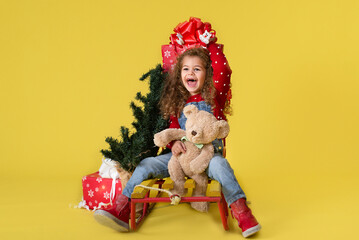 Girl with new year gifts on yellow background for copy