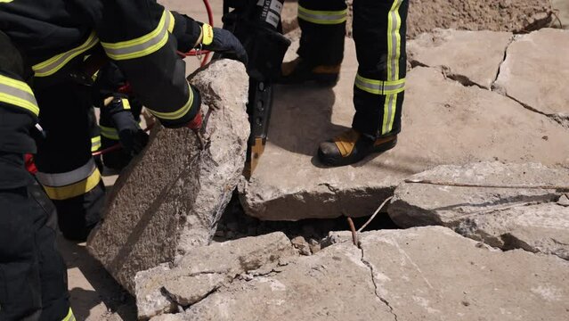 As a firefighter, a man in a uniform performs a rescue, with a power hydraulic cutter and hydraulic clamps, helping an earthquake victim