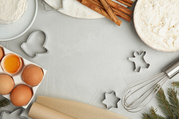 Flat lay composition with cookie cutters and ingredients on light grey table, space for text. Christmas biscuits