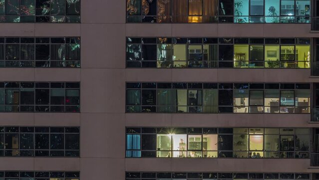 Windows lights in modern apartment buildings timelapse at night. Multi-level skyscrapers with illuminated rooms inside