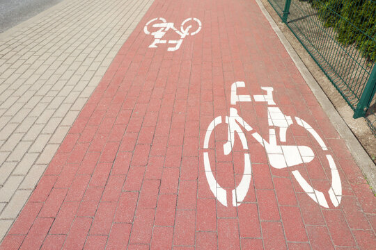 View of red bicycle lane with white signs on pavement