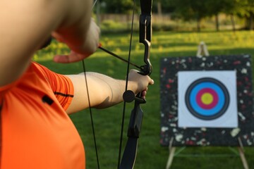 Man with bow and arrow aiming at archery target in park, closeup