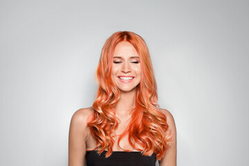 Beautiful woman with long orange hair on light background