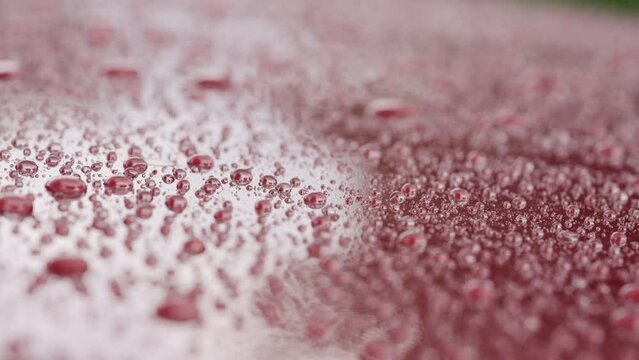 Slow motion of ceramic coated car under rain, water drops sliding from car