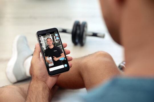 Man having workout with personal trainer via smartphone at home, closeup