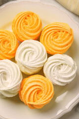 Delicious white and orange zephyrs on plate, top view