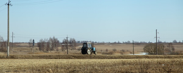 One wheeled tractor on road between a fields at spring day, rural life rustic landscape