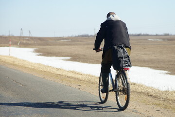 Rural cyclist man rides a Bicycle on the roadside of an empty suburban highway at spring day, bike safety ride