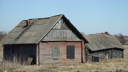 Fototapeta na wymiar Abandoned old Russian wooden rural barn and house at spring day