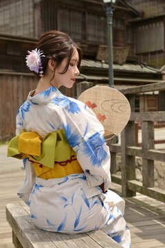 うちわ片手に小江戸佐原の町並みでポーズをとる浴衣を着た若い女性