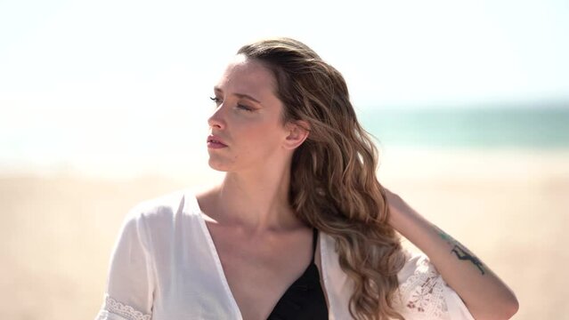 Chica joven en la playa posando y riendo al atardecer en la orilla del mar