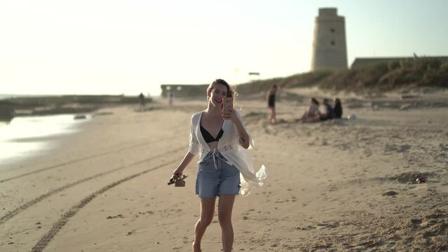 Chica joven en la playa posando y riendo al atardecer en la orilla del mar