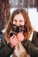 Girl woman and cat sitting on her shoulder in snowy winter forest