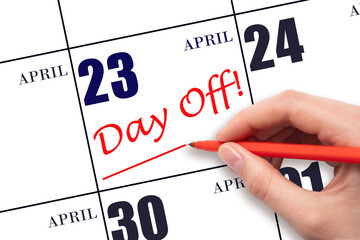 Hand writing text DAY OFF and drawing a line on calendar date 23 April. Vacation planning concept.
