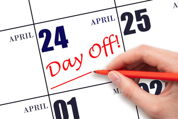 Hand writing text DAY OFF and drawing a line on calendar date 24 April. Vacation planning concept.