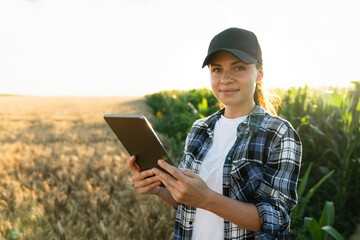 Woman farmer with digital tablet on an agricultural field. Smart farming and digital agriculture.