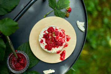 Cake with rice crisp bread and raspberry jam on a black background, outdoor garden fresh bush,...